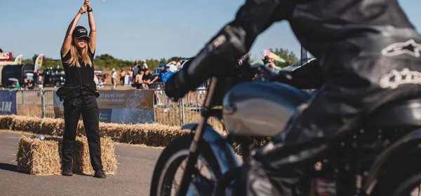 Woman holding flag in front of motorbikes