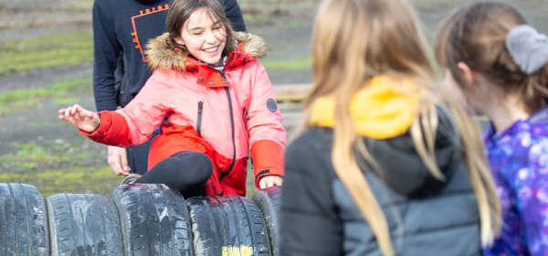 A group of children climbing over a row of tyres