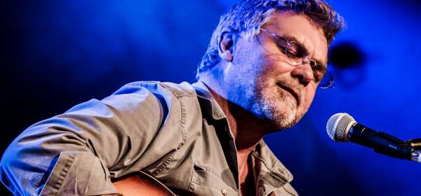 Photo of Chris Wood on stage playing his guitar