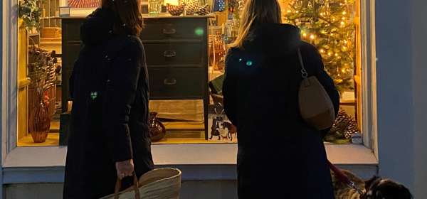 Two women looking into a shop window lit up for Christmas