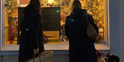 Two women looking into a shop window lit up for Christmas