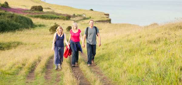 Three people walking along the clifftop towards the camera
