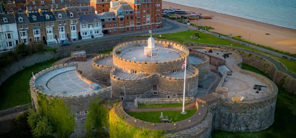 An aerial photo of Deal Castle in the foreground, the beach, buildings and the pier in the background.