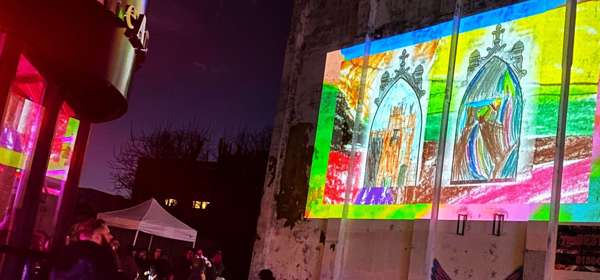 Projection of a colourful drawing onto the side of a building at night
