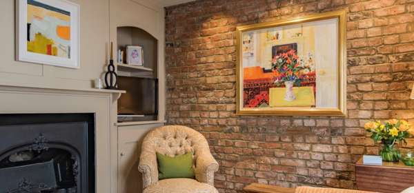 Sitting room with fire place, exposed brick wall with hung painting