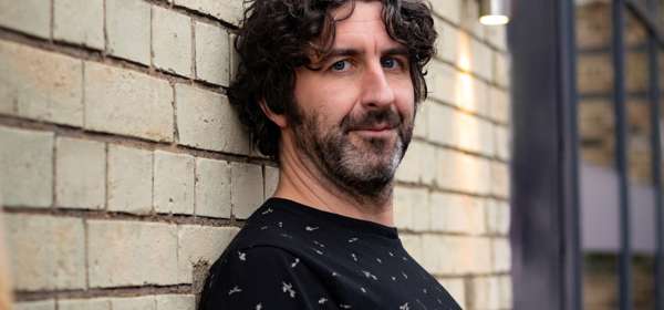 Photo of Mark Watson leaning against a wall