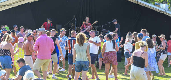 Crowd dancing in front of a band on a stage outdoors