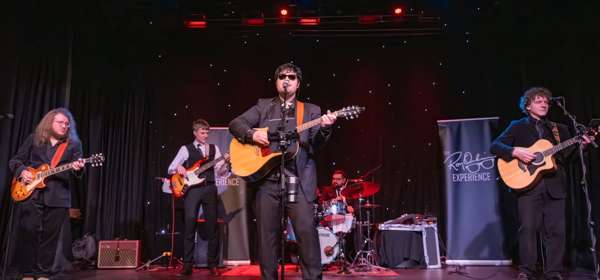 Photo of Oliver Harris as Roy Orbison on stage with his band