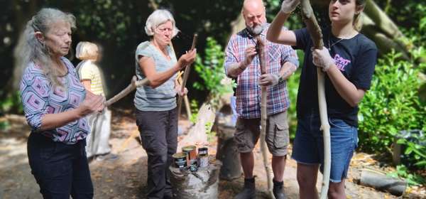 A group of people whittling long staffs