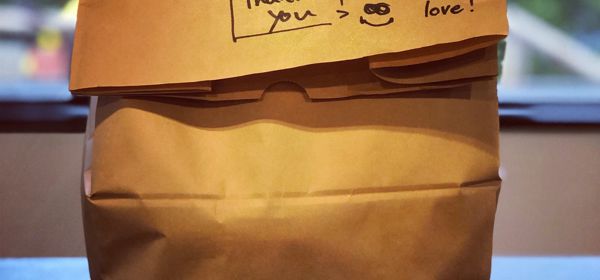 A brown paper takeaway back with the words 'Thank you - with love' written on.