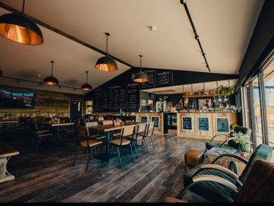 Interior of Whitemills kitchen with wooden floors and walls. Long wooden tables with seating for 6 people