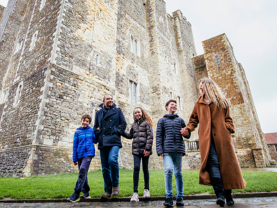 A family holding hands in front of the Great Tower at Dover Castle 